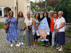 8 Frauen stehen mit Maskottchen Blubbi vor dem ENRW-Gebäude