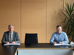 Geschäftsführer Ranzinger und Bürgermeister Kielack sitzen an Tisch und unterzeichnen Vertrag.